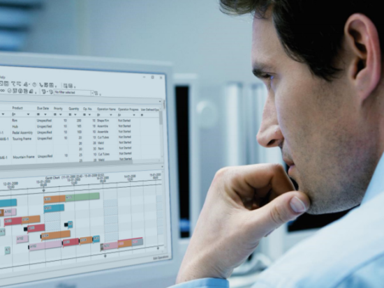 Mann im hellblauen Hemd sitzt nachdenklich vor einem Computerbildschirm mit einer Projektmanagement-Software und Gantt-Diagramm