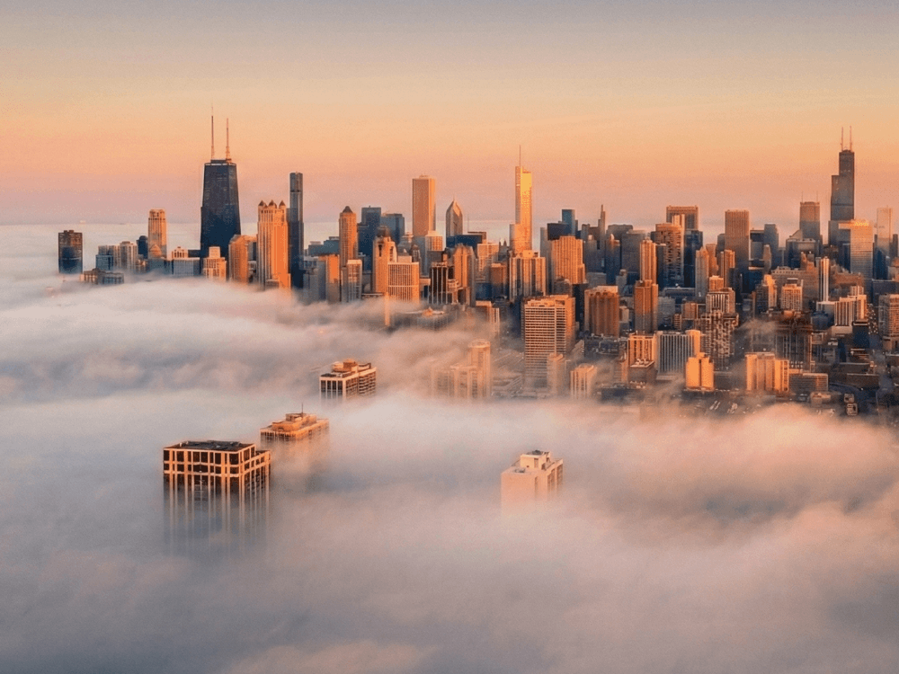 Hochhäuser, die aus dichtem Nebel ragen, beleuchtet vom warmen Morgenlicht