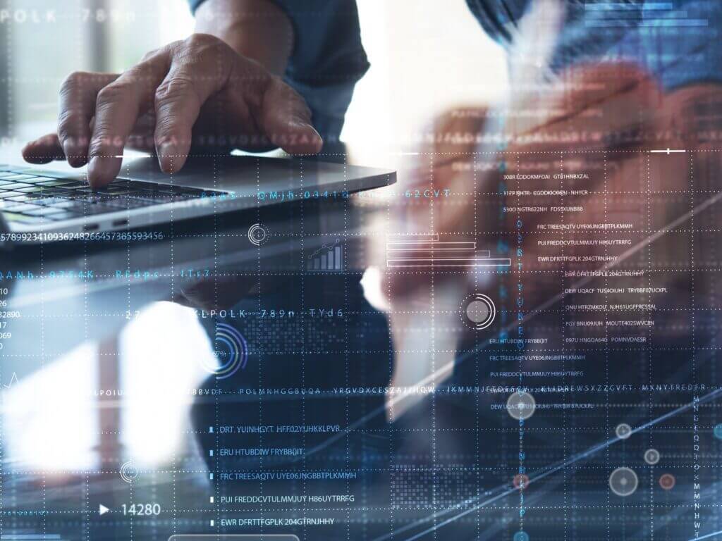 Hände über einer Tastatur mit eingeblendeten digitalen Daten und Diagrammen im Vordergrund